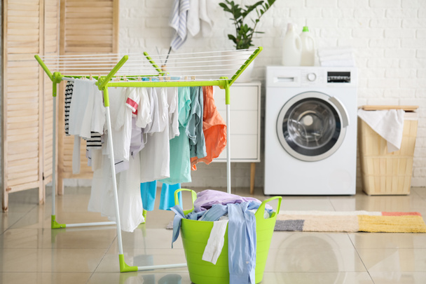 Vestiti puliti appesi all'asciugatrice in lavanderia - Foto, immagini