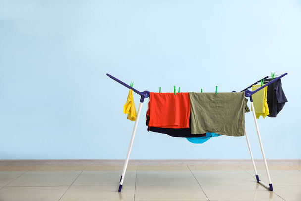 Чистий одяг, що висить на сушарці в приміщенні
 - Фото, зображення