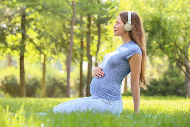 Mujer embarazada joven practicando yoga al aire libre - Foto, Imagen
