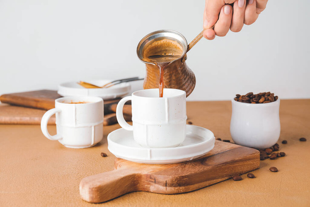 Woman pouring hot coffee from pot into cup on table - Photo, Image