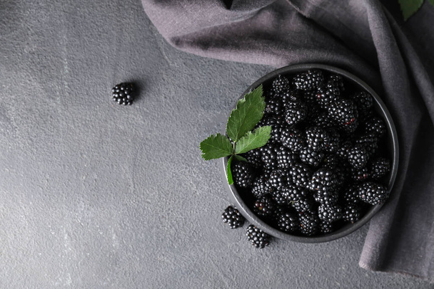 Bowl with tasty blackberry on dark background - Photo, image