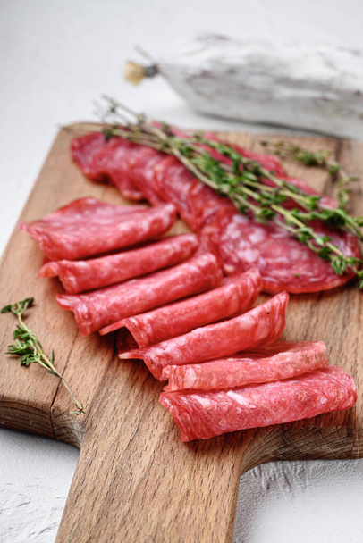Salchichon whole and sliced cuts, spanish sausage on white textured background. - Фото, зображення