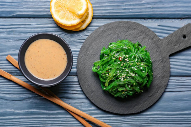 Вкусный салат из морских водорослей и соус на столе - Фото, изображение