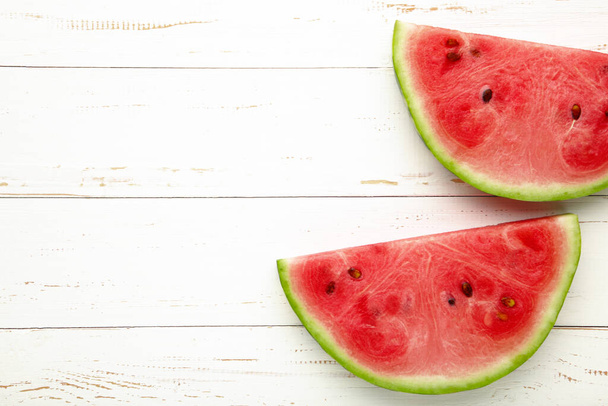 Fresh ripe striped sliced watermelon on white wooden background. - Fotoğraf, Görsel