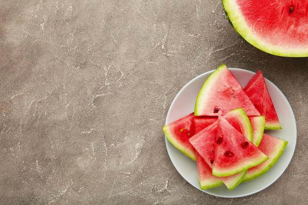 Fresh ripe striped sliced watermelon in the plate on grey concrete background. - Фото, изображение