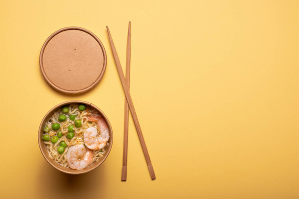 Chinese noedels met garnalen en groenten in een ambachtelijke kop, bovenaanzicht - Foto, afbeelding