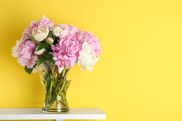 Beautiful peonies on white table against yellow background. Space for text - Φωτογραφία, εικόνα