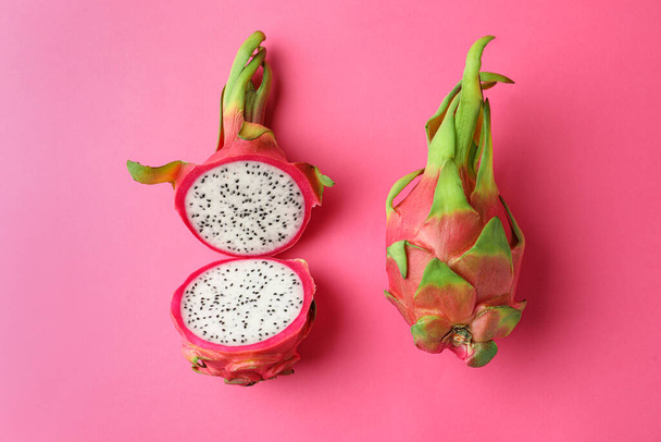 Delicious cut and whole dragon fruits (pitahaya) on pink background, flat lay - Foto, immagini