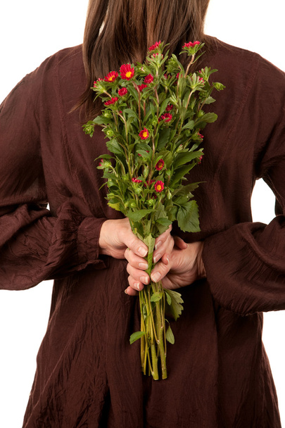 Woman holding flowers behind her back - Foto, Imagen