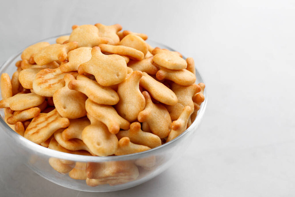 Delicious goldfish crackers in bowl on grey table, closeup - Fotó, kép