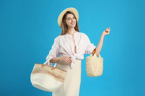 Beautiful young woman with stylish bags on light blue background - 写真・画像