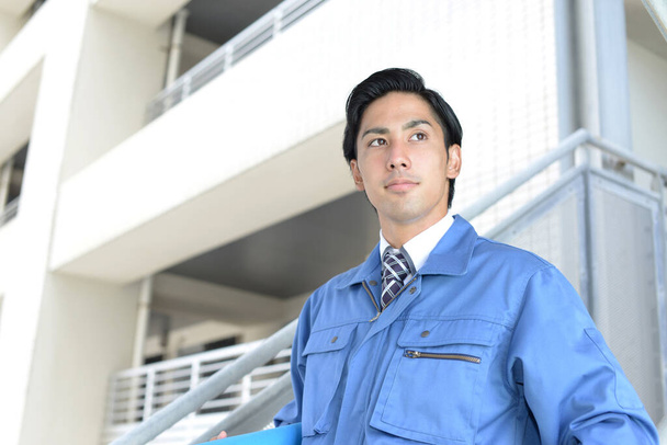 Uśmiechnięty azjatycki pracownik w niebieskim mundurze - Zdjęcie, obraz
