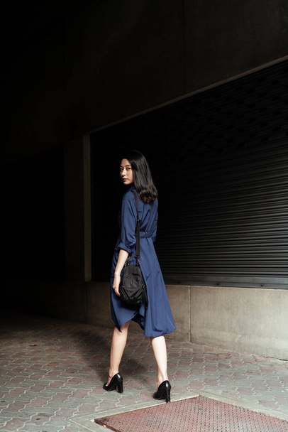 Schöne junge asiatische Frau auf blauem Kleid geht in dunkle Gasse. - Foto, Bild