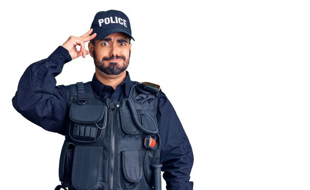 Jovem hispânico vestindo uniforme policial preocupado e estressado com um problema com a mão na testa, nervoso e ansioso pela crise
  - Foto, Imagem