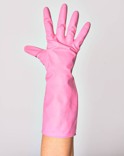 Mano de mujer joven caucásica con guante de limpieza rosa. Mostrando dedos haciendo el número cinco sobre fondo blanco aislado - Foto, Imagen