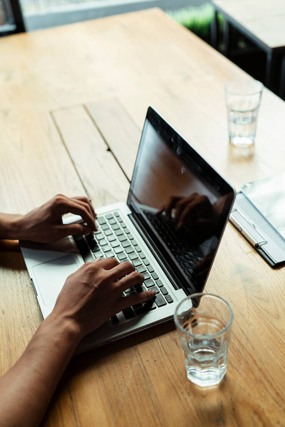 Mão fechada de um homem digitando no laptop na mesa de madeira que trabalha no café ou no escritório moderno
. - Foto, Imagem