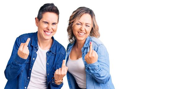 Couple of women wearing casual clothes showing middle finger doing fuck you bad expression, provocation and rude attitude. screaming excited  - Zdjęcie, obraz
