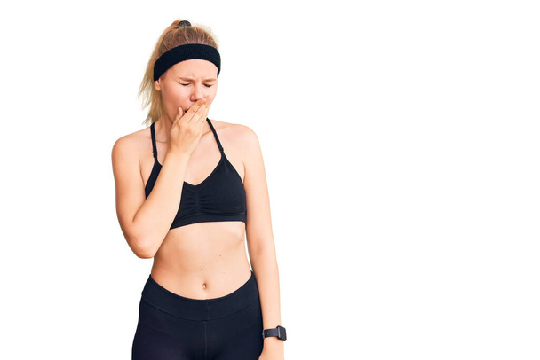 Young beautiful blonde woman wearing sportswear bored yawning tired covering mouth with hand. restless and sleepiness.  - Photo, image