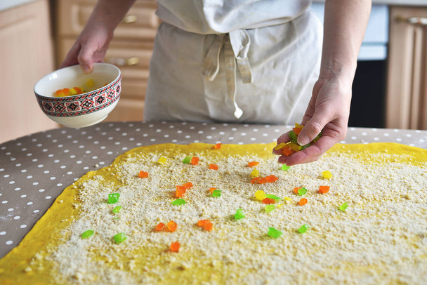 woman's hand sprinkles the dough with candied fruits and raisins - Photo, Image
