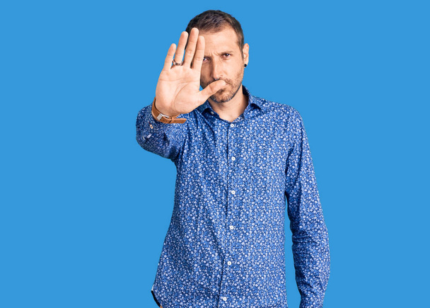 Young handsome man wearing casual clothes doing stop sing with palm of the hand. warning expression with negative and serious gesture on the face.  - Photo, Image
