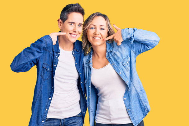 Couple of women wearing casual clothes smiling cheerful showing and pointing with fingers teeth and mouth. dental health concept.  - Foto, Imagen