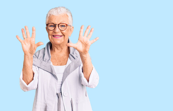 Senior beautiful woman with blue eyes and grey hair wearing casual clothes and glasses showing and pointing up with fingers number ten while smiling confident and happy.  - Photo, Image