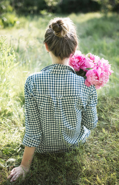 Portrait of a beautiful girl with a bouquet of peonies, view from the back - Foto, imagen