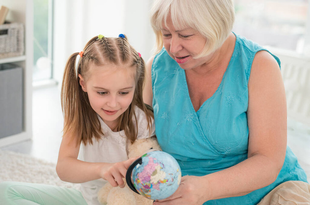 Grandmother and granddaughter examining globe - Foto, afbeelding