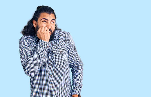Hombre árabe joven que usa ropa casual que se ve estresado y nervioso con las manos en la boca mordiendo las uñas. problema de ansiedad.  - Foto, Imagen