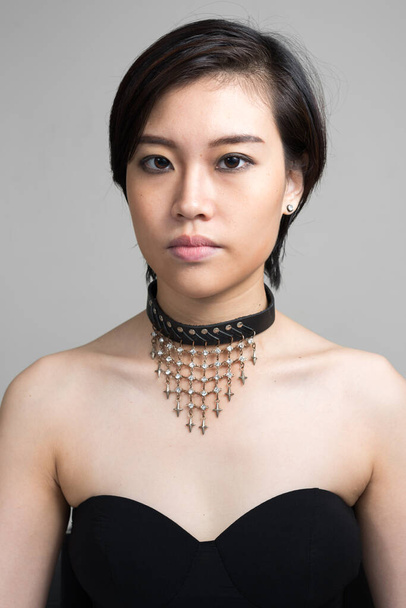 Estudio disparo de joven hermosa mujer asiática con pelo corto sobre fondo blanco
 - Foto, Imagen