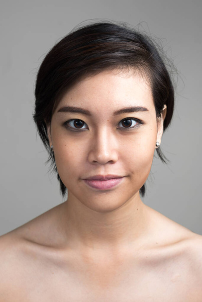 Studio colpo di giovane bella donna asiatica con i capelli corti senza maglietta contro sfondo bianco - Foto, immagini