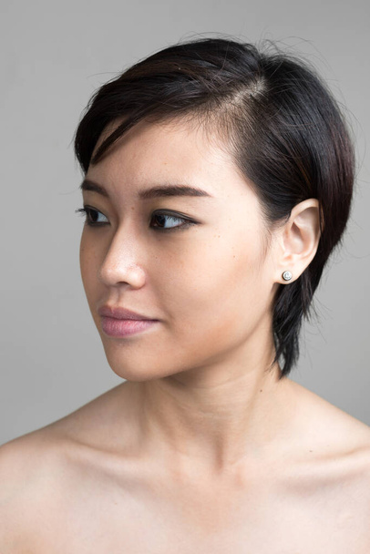 Studio shot of young beautiful Asian woman with short hair shirtless against white background - Zdjęcie, obraz