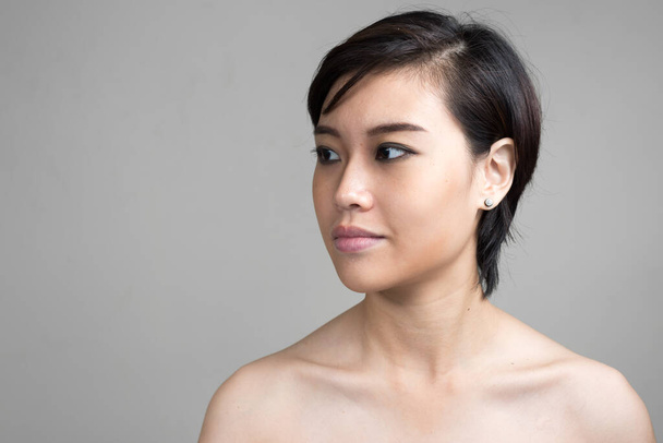 Studio shot of young beautiful Asian woman with short hair shirtless against white background - Valokuva, kuva