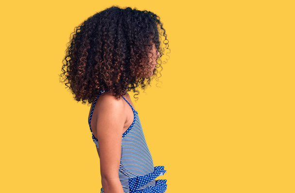 Criança afro-americana com cabelo encaracolado vestindo roupa de banho olhando para o lado, relaxe pose perfil com rosto natural com sorriso confiante.  - Foto, Imagem