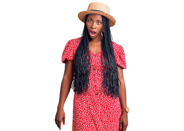 Giovane donna afroamericana con cappello estivo in faccia shock, dall'aspetto scettico e sarcastico, sorpresa a bocca aperta  - Foto, immagini