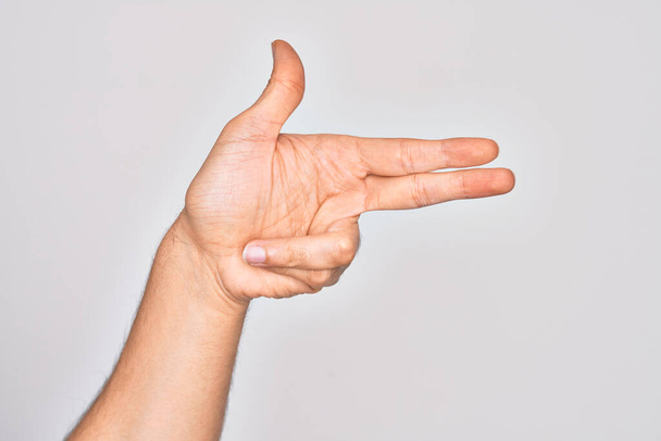Hand of caucasian young man showing fingers over isolated white background gesturing fire gun weapon with fingers, aiming shoot symbol - Photo, Image