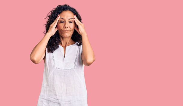 Middle age beautiful woman wearing casual sleeveless t shirt suffering from headache desperate and stressed because pain and migraine. hands on head.  - Photo, Image