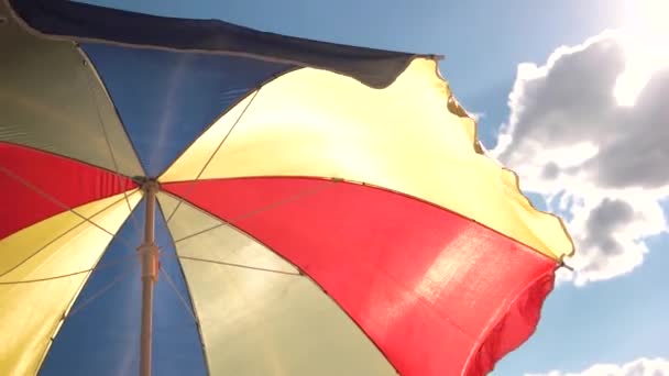 όμορφη πολύχρωμη ομπρέλα παραλίας σε φόντο μπλε ουρανού - Πλάνα, βίντεο