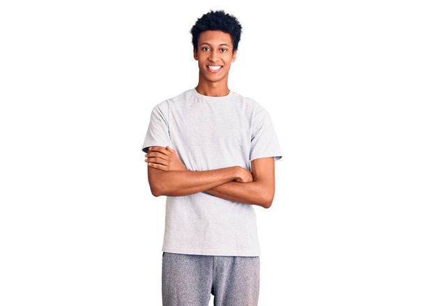 Молодий афроамериканець, одягнений у повсякденний одяг, усміхається зі схрещеними руками, дивлячись на камеру. позитивна людина.  - Фото, зображення