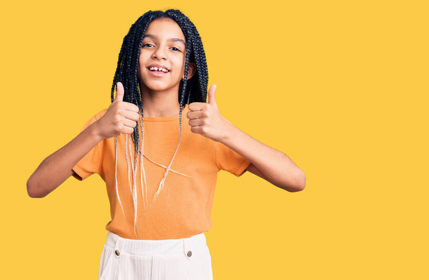 Cute african american girl wearing casual clothes success sign doing positive gesture with hand, thumbs up smiling and happy. cheerful expression and winner gesture.  - Photo, Image