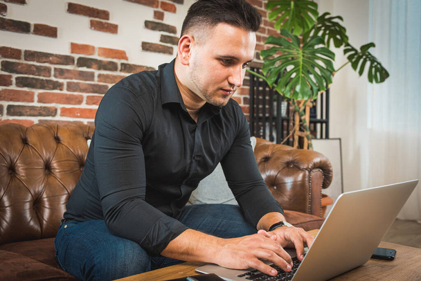Fiatal üzletember dolgozik otthon laptop és papírok az asztalon - Fotó, kép