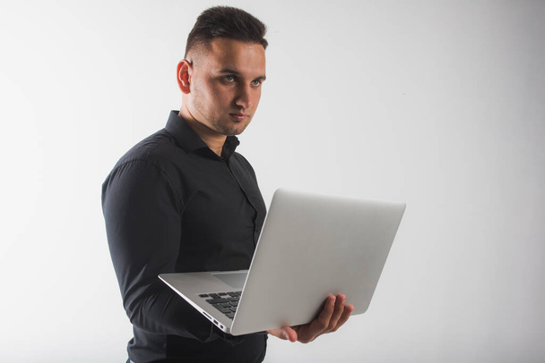 Portré egy fiatal, fókuszált üzletember öltönyben dolgozik egy laptop számítógépen, miközben áll elszigetelt fehér alapon, van egy hely a felirat - Fotó, kép