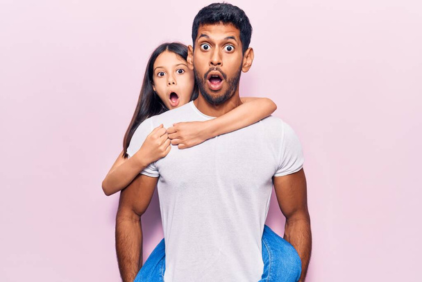 Latein Vater und Tochter in lässiger Kleidung verängstigt und erstaunt mit offenem Mund für Überraschung, ungläubiges Gesicht  - Foto, Bild