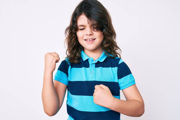 Mignon enfant hispanique aux cheveux longs portant des vêtements décontractés célébrant surpris et étonnés pour le succès avec les bras levés et les yeux fermés  - Photo, image