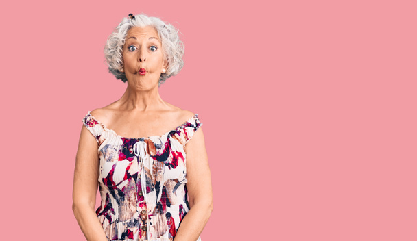 Ηλικιωμένη γκριζομάλλα γυναίκα που φοράει καθημερινά ρούχα και κάνει γκριμάτσες με χείλη, τρελή και κωμική χειρονομία. αστεία έκφραση.  - Φωτογραφία, εικόνα