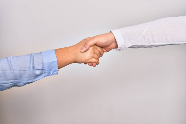 Handshake of two hands of young caucasian businesswomen for agreement over isolated white background - Photo, Image