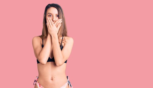 Young beautiful girl wearing bikini shocked covering mouth with hands for mistake. secret concept.  - Foto, Imagem