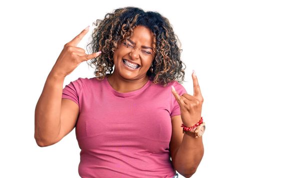 Mladá Afroameričanka plus velká žena v neformálním oblečení křičí šíleným výrazem a dělá rockový symbol s rukama nad hlavou. hudební hvězda. koncepce těžké hudby.  - Fotografie, Obrázek
