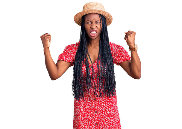 Genç Afro-Amerikan kadın kızgın ve kızgın şapkalı kızgın yumruklar sallarken öfkeyle bağırıyor. öfke ve agresif konsept.  - Fotoğraf, Görsel