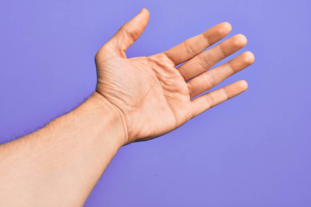 Hand eines kaukasischen jungen Mannes mit Fingern über isoliertem lila Hintergrund, Zählzahl 5 mit fünf Fingern - Foto, Bild